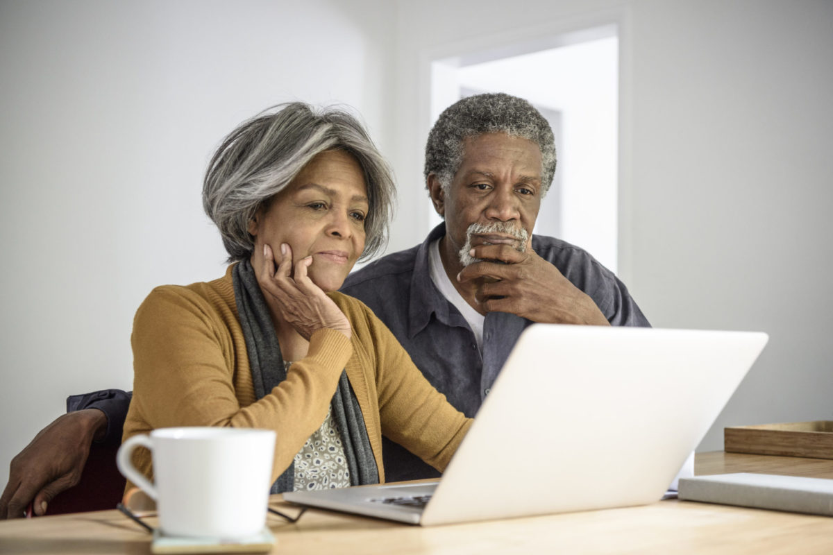 Senior African American couple using laptop, contemplating