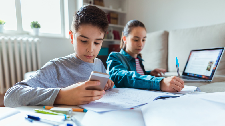 Photo of boy and girl learning with technology at home
