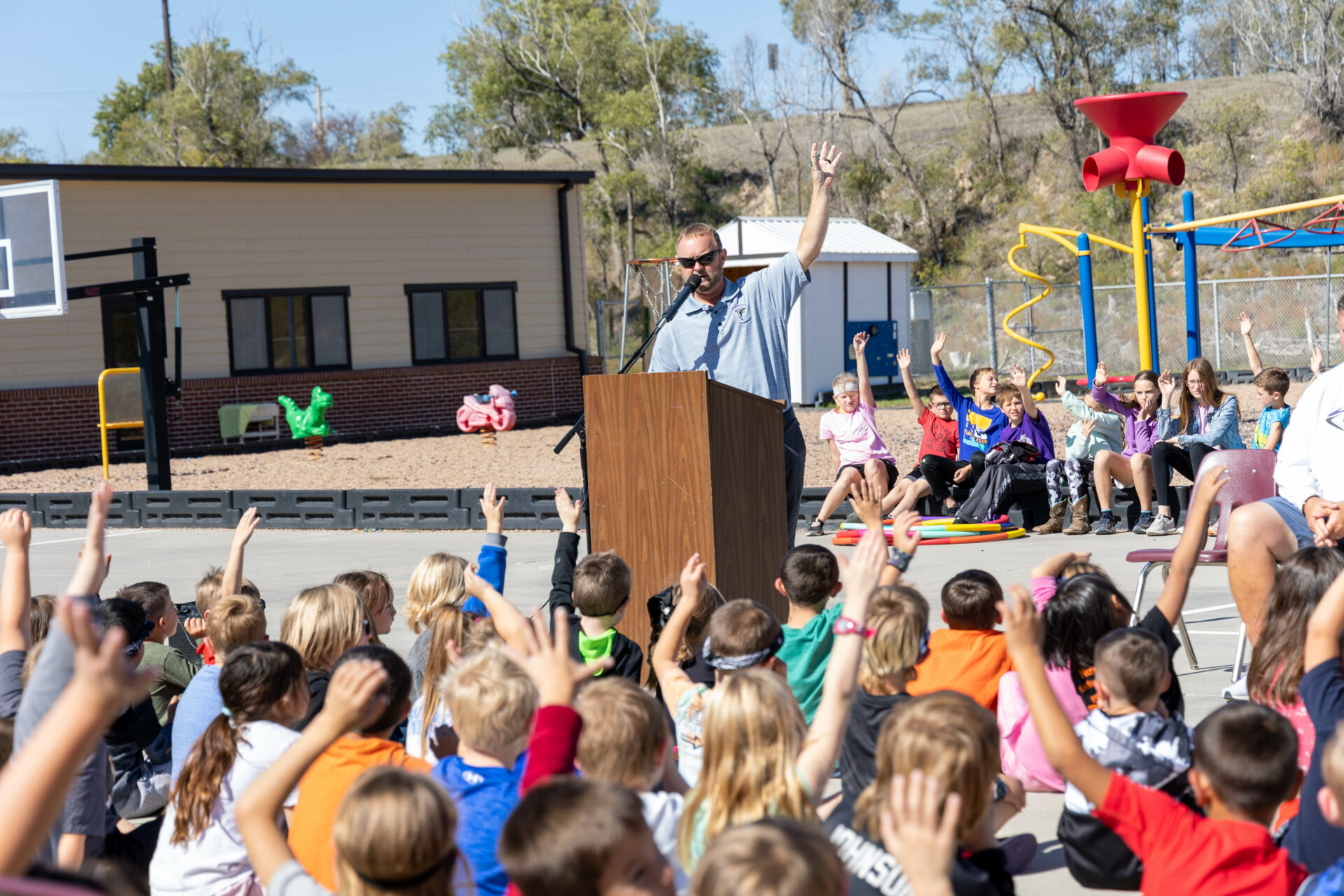 Students raise their hands at the Project Fit America playground ribbon cutting.